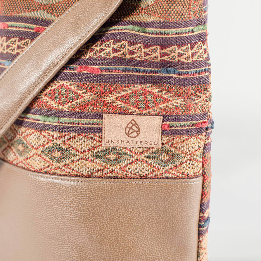 A tan label on a aztec design tote bag on top and brown luxury leather alternative on the bottom named after Chanel 