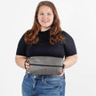 A woman holding a gray leather toiletry bag with a zipper closure, a handle, and a brand label on the front named after Charles