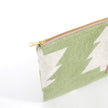 Close-up of gold-tone zipper on green woolen pouch with white tree pattern 