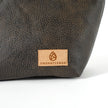 Close up of a tan suede Unshattered label on a brown luxury leather alternative makeup bag