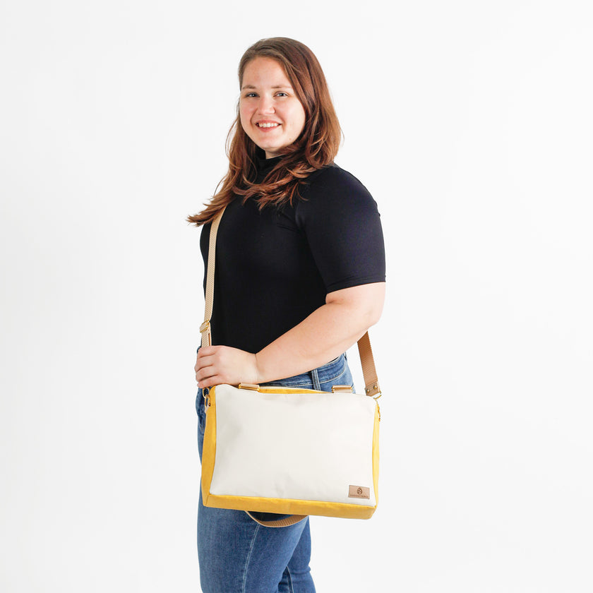 Woman holding a yellow and white convertible handbag on a white background
