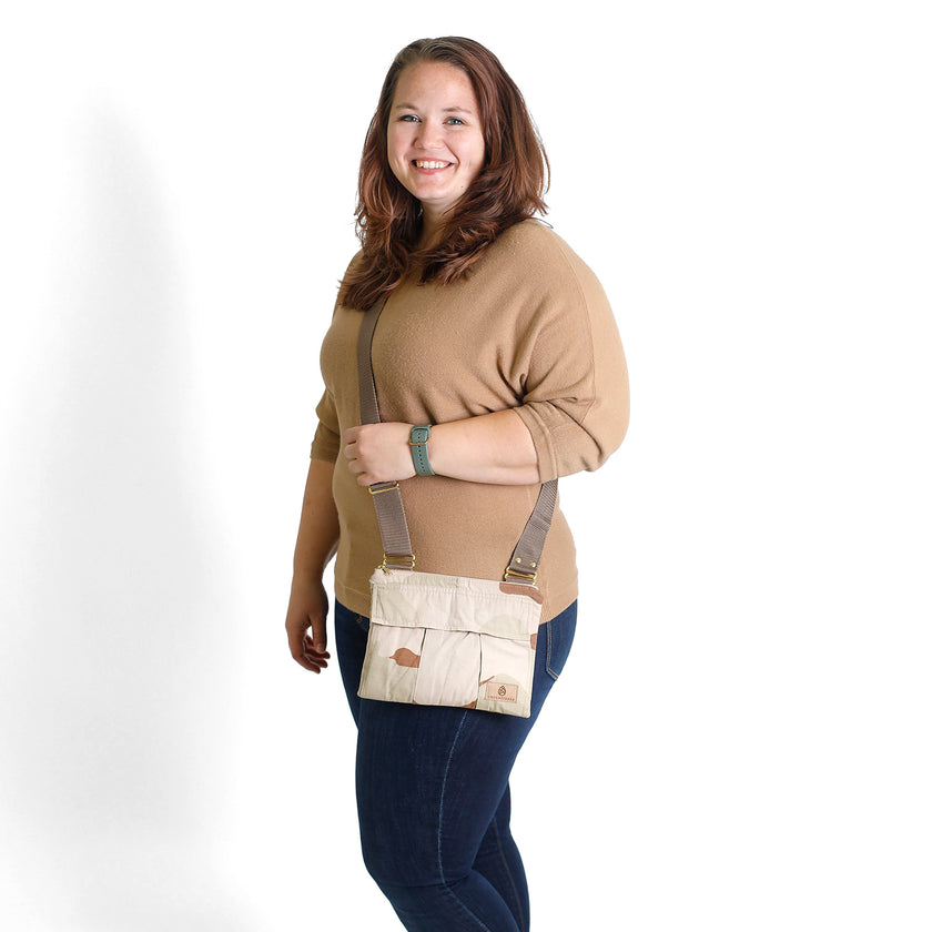 Woman wearing a dcu beige crossbody bag with brown strap on a white background 