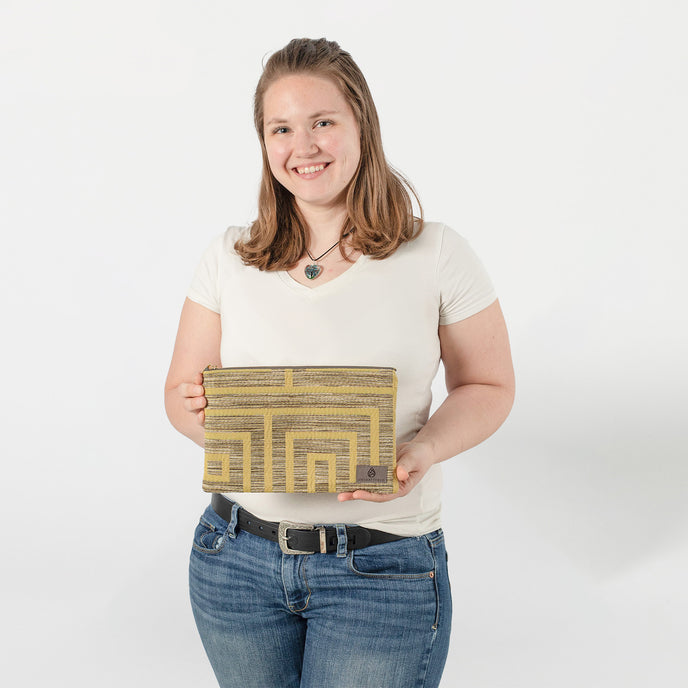 A woman holding a yellow lined design DarlaJean large zip pouch on a white background 