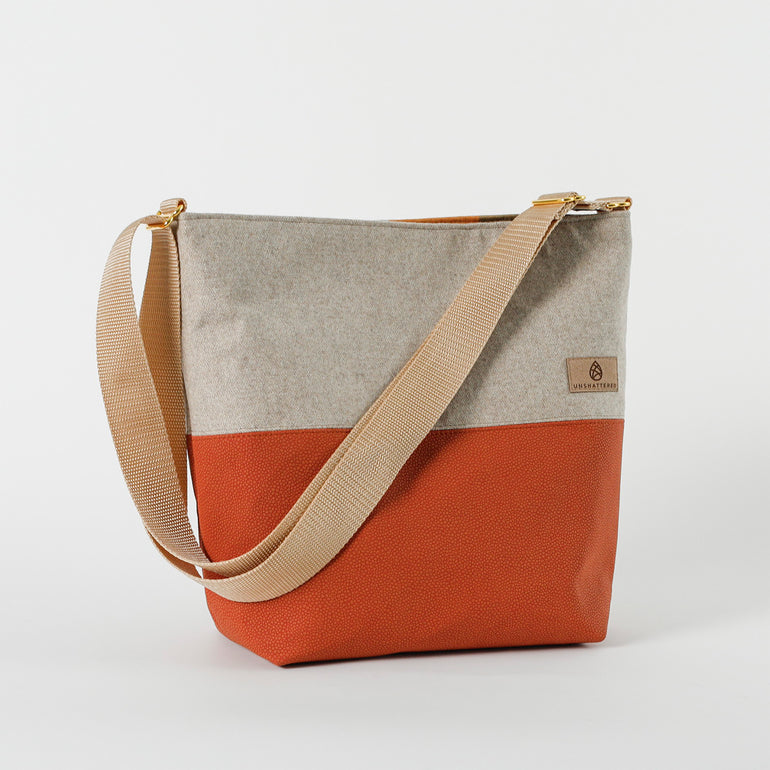 A handcrafted shoulder tote bag with a luxury leather alternative material and orange fabric, featuring an adjustable strap and gold-tone hardware named after Deanna.