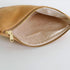 Interior of beige suede pouch with gold zipper on a light gray background