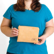 A woman holding a beige suede zip pouch named after Deborah 