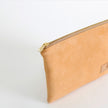 Beige pouch with a gold zipper on a light gray background