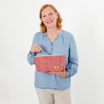 Woman holding a pink makeup bag with a white background named after Dee