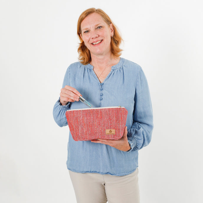 Woman holding a pink makeup bag with a white background named after Dee