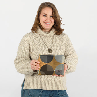 A woman holding a multicolored geometric circle design zip pouch with gold-tone hardware named after Desiree.