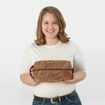 A woman holding a paisley toiletry kit named after Destiny wearing a white shirt and jeans 