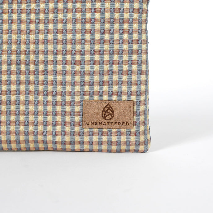 Tan suede label on a checked zippered pouch handcrafted from upcycled material