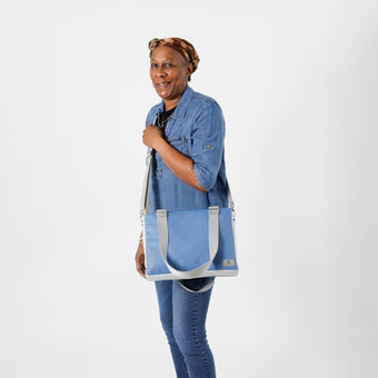 A woman holding a blue luxury leather alternative handbag with gray straps and silver toned hardware named after Diamond 