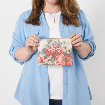 A woman holding a flower zip pouch with a gold zipper and tan label named after Diana