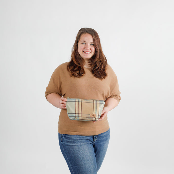Woman holding a plaid makeup bag against a white background