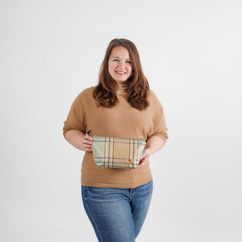 Woman holding a plaid makeup bag against a white background