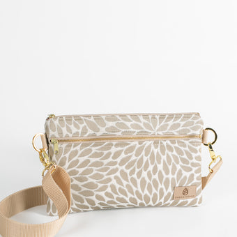 This crossbody 3-in-1 bag with platos petal design fabric with gold hardware and a tan zipper with a tan strap 