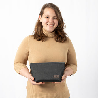 A woman holding a black makeup kit with a zipper closure, made from outdoor furniture material, named after Effley