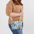 Woman holding a crossbody bag with a teal whisper microfiber pattern named after Eliza
