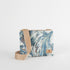 Crossbody bag with blue and white marbled pattern with a tan strap on a white background.