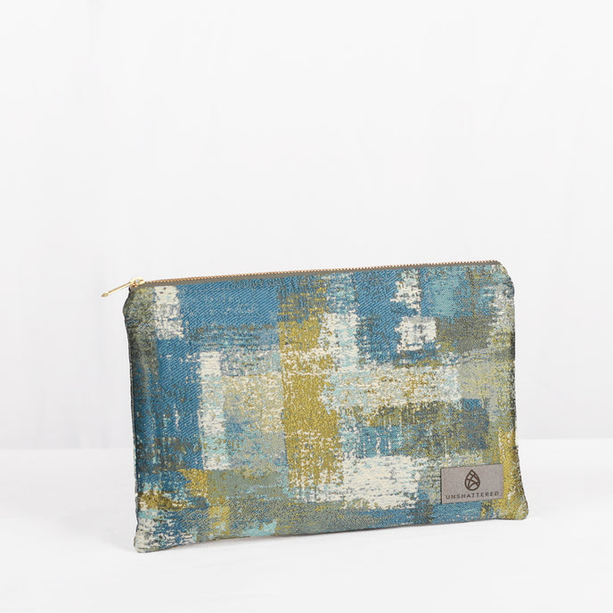 A large zip pouch with a multicolored sea glass design, featuring a small brand logo on the lower right corner.