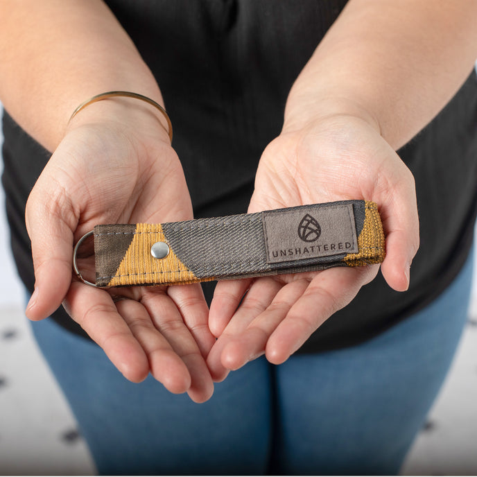A woman holding a circle design loop keychain with silver tone hardware 
