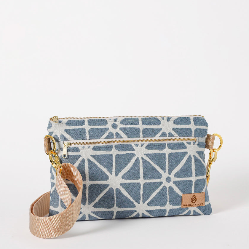 Blue geometric patterned handbag with beige strap on a white background