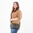 Woman holding a brown 3-in-1 crossbody bag against a white background
