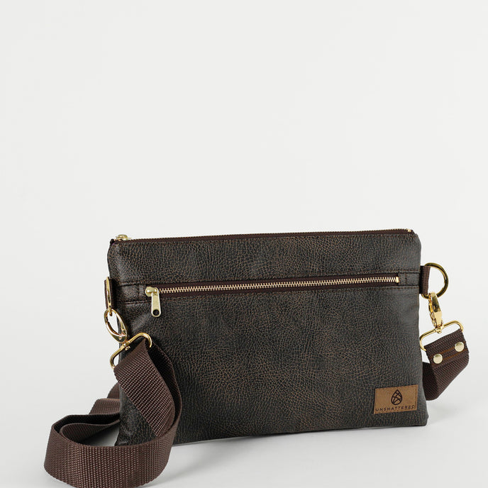 A brown 3-in-1 bag with a zipper closure, gold-tone hardware, and crossbody strap attached on a white background 