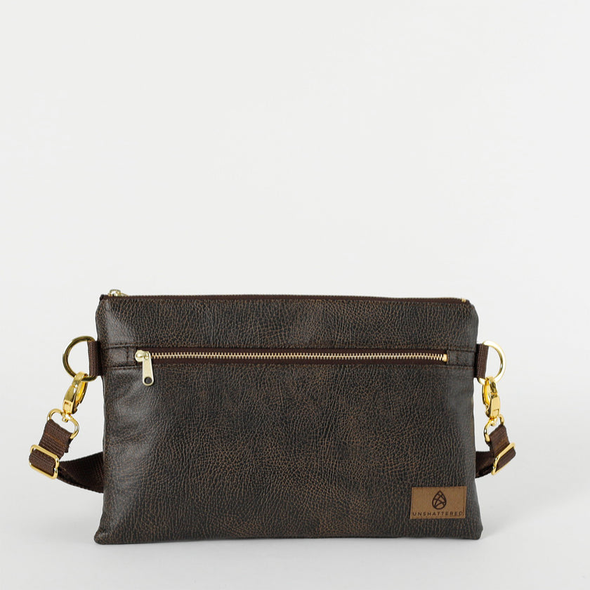 A brown 3-in-1 bag with a zipper closure, gold-tone hardware, and brown belt strap attached on a white background 