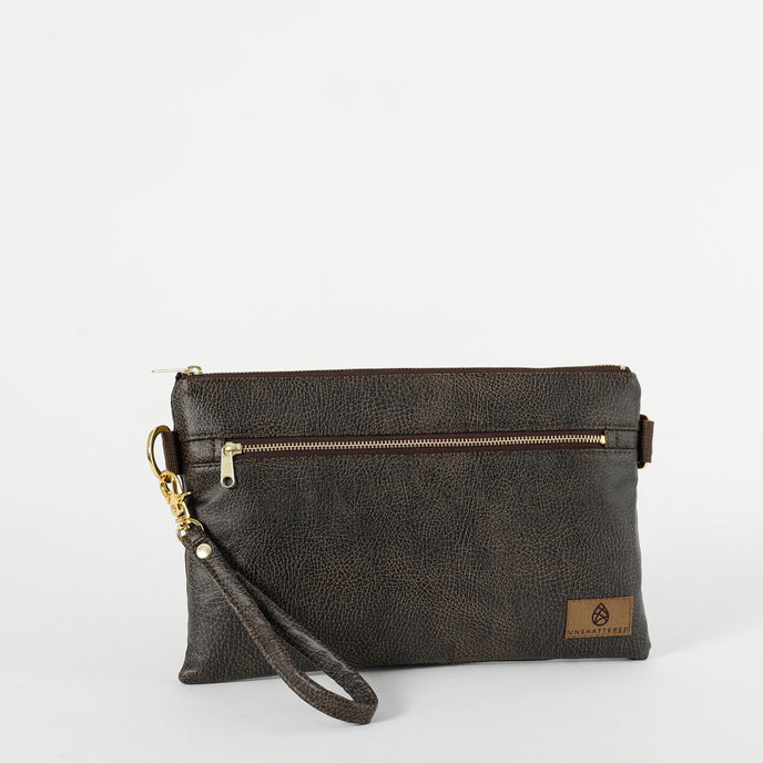 A brown 3-in-1 bag with a zipper closure, gold-tone hardware, and wristlet strap attached on a white background 