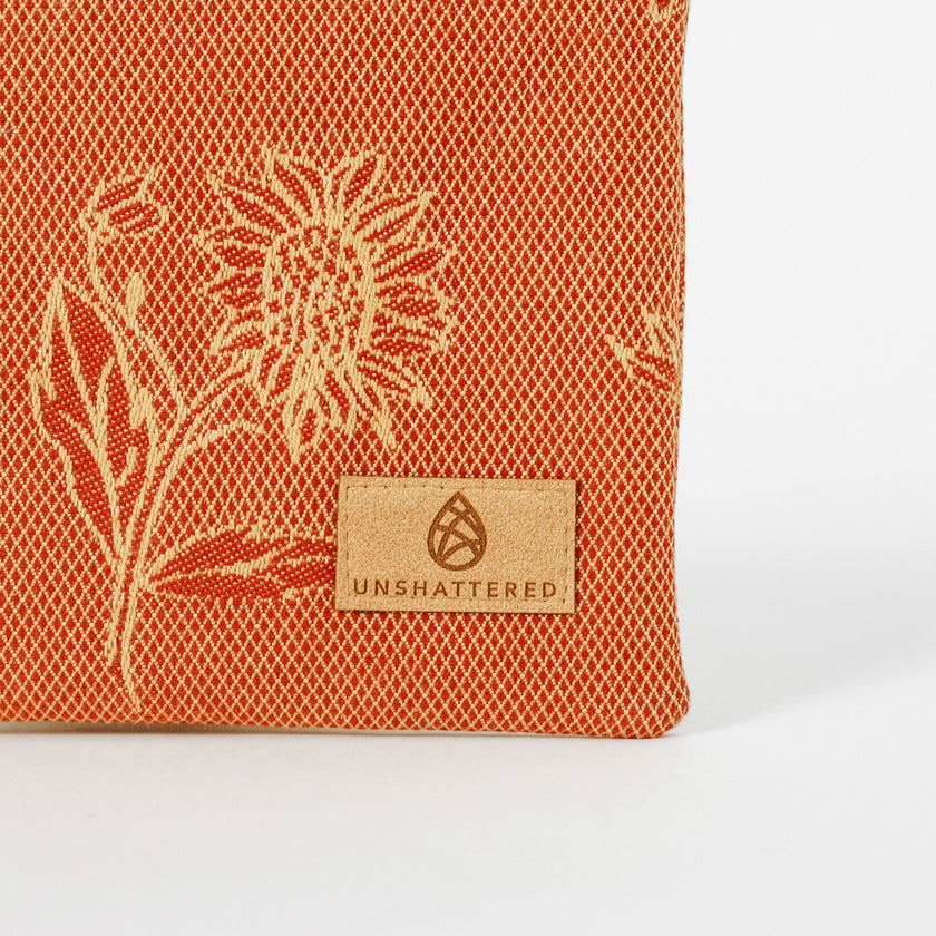 Red/Orange fabric with floral patterns and 'Unshattered' brand logo on a white background named after Faith 