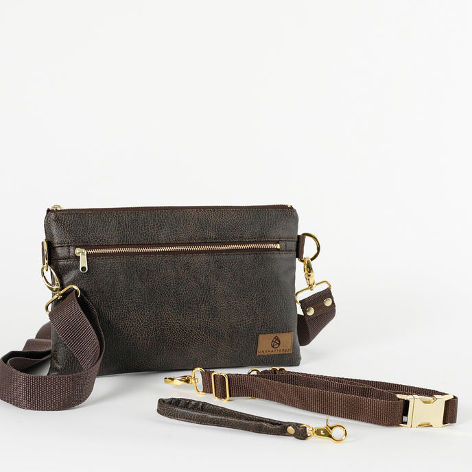 A brown 3-in-1 bag with a zipper closure, gold-tone hardware, and three detachable straps laid out on a white background.