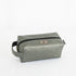 A gray toiletry kit with a zipper closure and a label displaying the brand name Unshattered named after Francine 