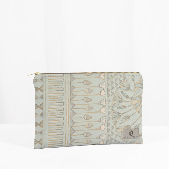 A large zip pouch with a damask print in blue and beige tones, featuring a zip closure and a label showing the brand name 'Unshattered'.