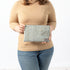 A woman holding a blue print design large zip pouch with a gray label and gold tone zipper