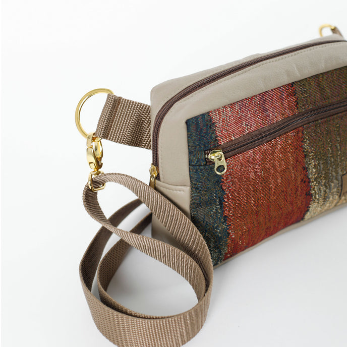 A brown strap with gold hardware on a fall color errand bag and taupe luxury leather alternative accents