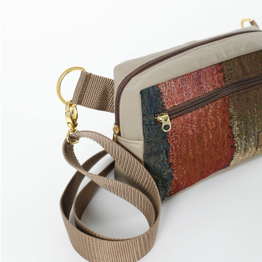 A brown strap with gold hardware on a fall color errand bag and taupe luxury leather alternative accents