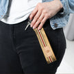 Alt text: A woman holding this striped key clip with a tan label and gold hardware