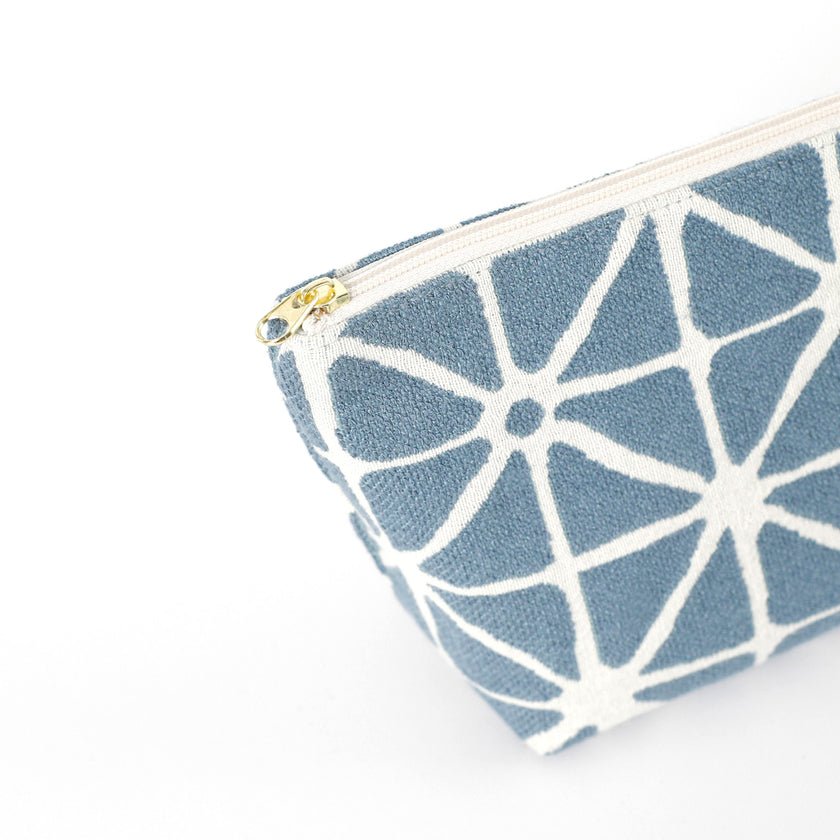 Gold-tone zipper on a blue geometric patterned makeup bag named Erin on a white background