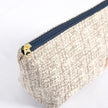 A gold tone zipper on an upcycled neutral fabric makeup bag