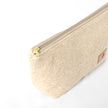 Gold-tone zipper on a makeup bag made from upcycled beige material on a white background