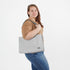 Woman holding a gray zippered tote bag against a white background