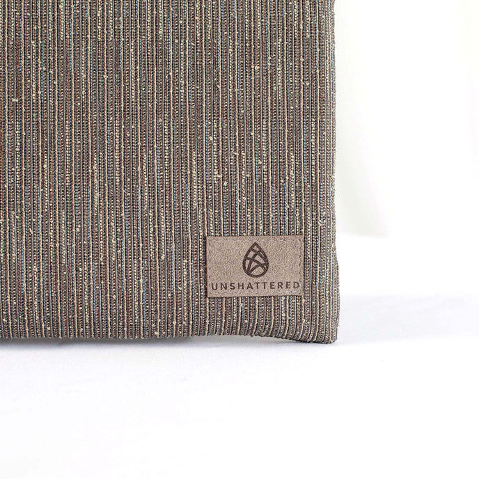 Gray suede Unshattered label on a textured gray crossbody pouch made from upcycled materials