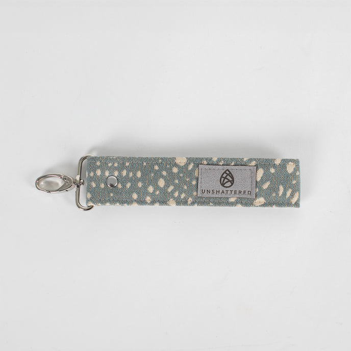 This gray fabric wristlet key clip features a playful dotted pattern and sleek siver-tone hardware.