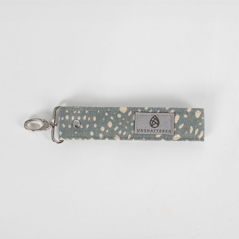 This gray fabric wristlet key clip features a playful dotted pattern and sleek siver-tone hardware.