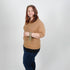 Woman wearing a brown sweater and blue jeans holding key clip on her wrist  a white background