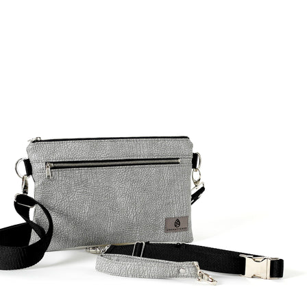 A medium-sized silver 3-in-1 bag with a zip closure, upcycled fabric exterior, and three interchangeable straps displayed against a white background named after Greg.