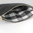 Black zippered pouch with checkered interior on a white background named after Harmony