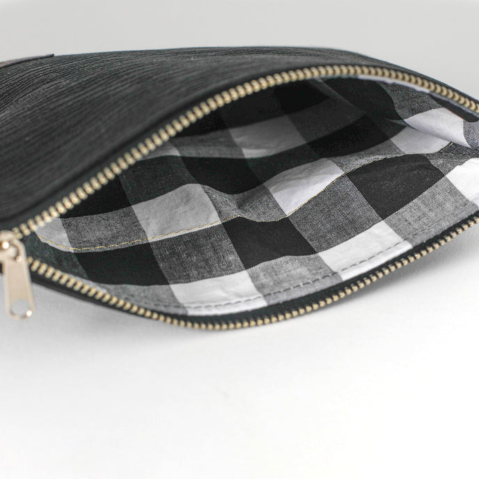 Black zippered pouch with checkered interior on a white background named after Harmony